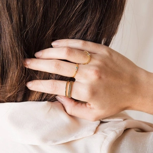 Close-up of three gold-plated rings with blue and black crystals on a model's hand