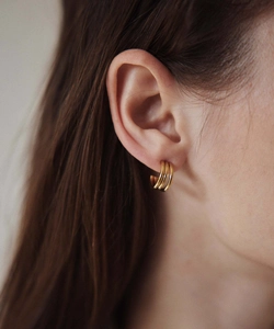 Close-up of triple-layered golden C-shaped hoop earrings on model with polished finish