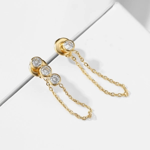 Golden stainless steel tassel earrings with round zirconia on a minimalist white platform