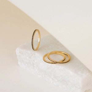 Close-up of three gold eternity rings with micro-pave black stones on stone display