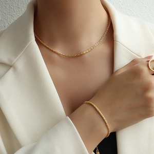 Ensemble collier et bracelet en maille dorée porté par un mannequin élégant