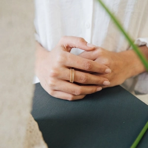 Three-piece stackable thin gold rings with twisted texture worn in a lifestyle setting
