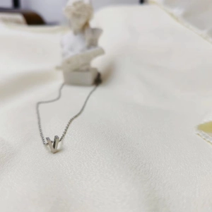 Macro shot of silver V-shaped pendant on elegant fine chain with satin fabric backdrop