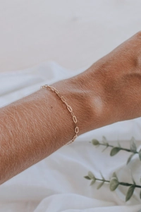 Nahaufnahme eines minimalistischen vergoldeten Büroklammer-Armbands am Handgelenk