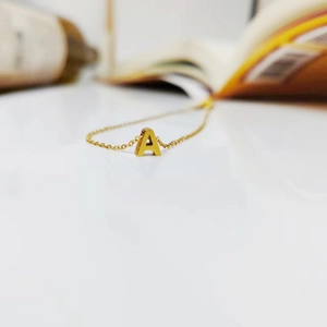 Detailed macro view of a polished gold-plated initial A pendant on a fine link chain