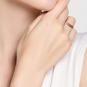 Close-up of gold stacked rings with blue and black rhinestones worn by a model