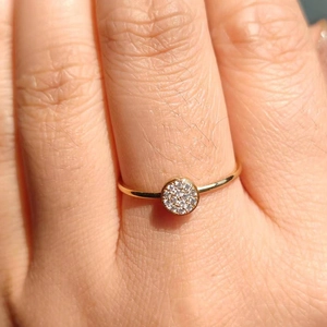 Detailaufnahme eines vergoldeten minimalistischen Rings mit rundem Zirkonia-Besatz auf der Hand