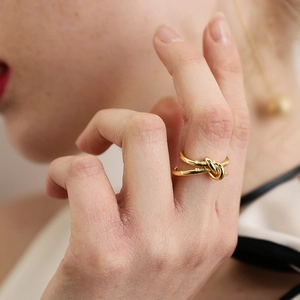 Élégante bague nœud en acier inoxydable doré portée par une femme sur la main