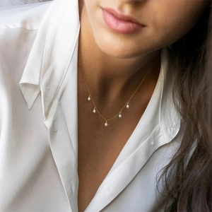 Detail of elegant gold pearl choker necklace featuring five white pearls on a model