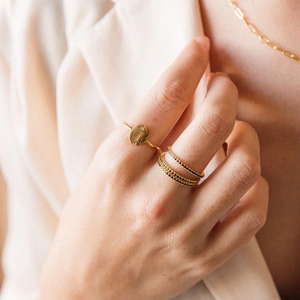 Gold ring set with floral engraving and black zircon accents on a model's hand