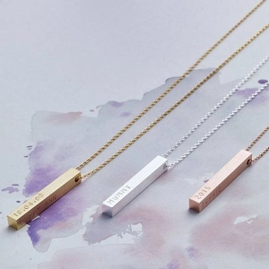Macro view of three customized vertical bar pendants in gold, silver and rose gold