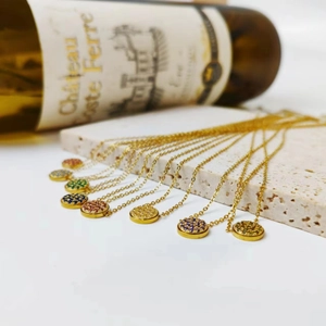 Detail of round pendant necklaces with multi-color birthstones on textured stone surface