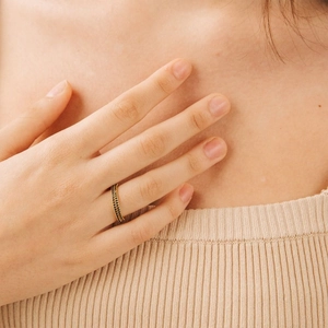 Close-up of a gold thin ring with double-row black stones worn on a model's hand
