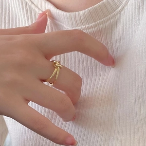 Détail d'une bague nœud dorée avec finition polie brillante portée au doigt