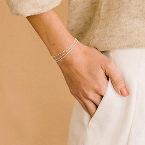 Dettaglio di un bracciale a tre strati in acciaio inossidabile argento su un polso