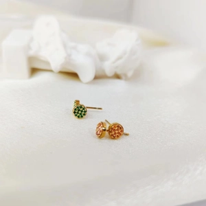 Macro detail of gold plated round stud earrings with pave set green and pink crystals