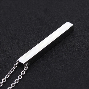 Macro detail of silver geometric vertical bar pendant in polished stainless steel