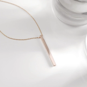 Macro shot of minimalist rose gold vertical bar pendant necklace with a polished finish