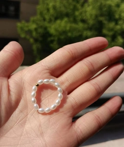 Detail of minimalist beaded ring with white oval pearls and a single gold accent bead