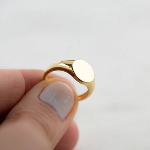 Detailed macro view of a polished gold-finish stainless steel oval signet ring