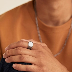 Close-up of minimalist matte stainless steel signet ring on finger with geometric round top