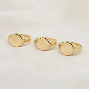 Macro shot of three minimalist gold signet rings with polished round flat surfaces