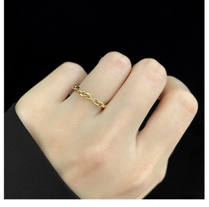 Close-up of a gold-plated stainless steel chain ring on a finger with a dark background