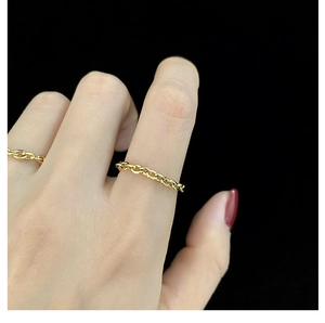 Detailed close-up of a minimalist gold oval chain link ring on a model's hand with black background