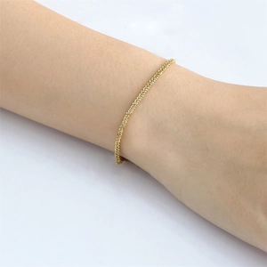 Minimalist stainless steel gold plated thin chain bracelet worn on a woman's wrist