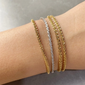 Set of four stackable gold and silver twisted rope chain bracelets on a female wrist