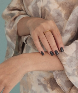 Detail of a minimalist gold-plated oval chain link ring worn on the finger