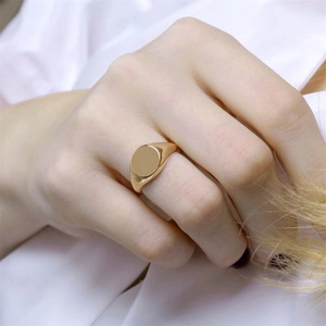 Minimalist gold plated circular signet ring with a polished finish worn on finger