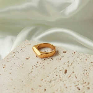 Detail view of a minimalist gold geometric ring on stone with silk background