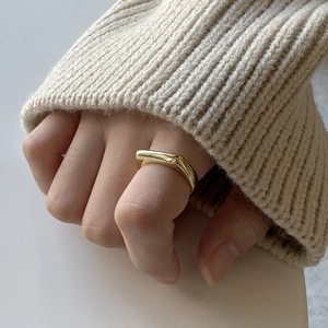 Close-up of a minimalist gold geometric square ring on finger with soft lighting