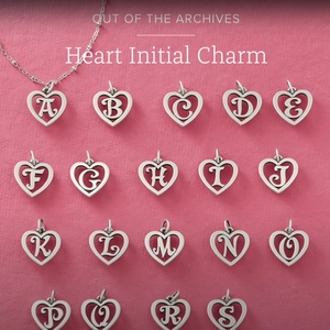 Detailed macro view of heart-shaped initial charms in polished stainless steel