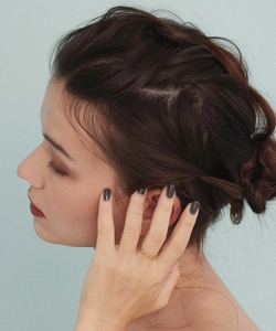Detailed view of a gold chain link ring on finger with elegant dark manicured nails