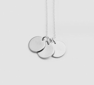 Macro detail of three minimalist polished silver discs hanging on a fine O-link chain