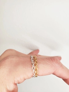 Detail of stacked gold and silver oval link chain rings worn on a hand model