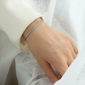 Close-up of a delicate silver tennis bracelet with sparkling zircons on a model's wrist