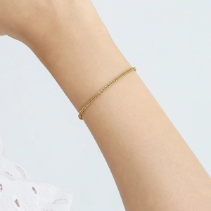 Close-up of a gold-plated stainless steel woven chain bracelet worn on a wrist