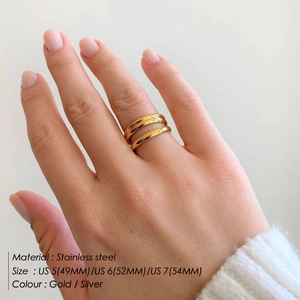 Detail shot of multi-layer gold stainless steel rings worn by a model on a clean background