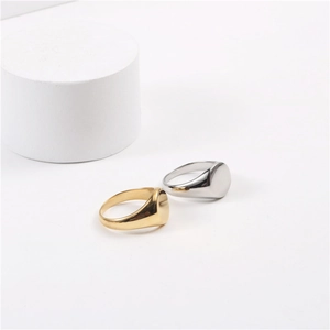 Minimalist gold and silver stainless steel signet rings on a clean white display pedestal