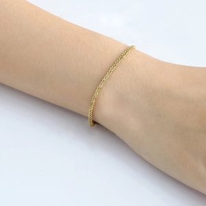 Close-up of a gold-plated stainless steel woven bracelet on a model's wrist