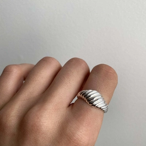 Détail d'une bague torsadée en argent avec texture ondulée portée à la main par un mannequin