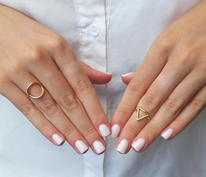 Detailed view of gold geometric rings with circular and triangular designs on fingers