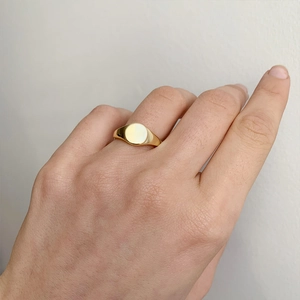 Close-up of minimalist gold-plated stainless steel signet ring on woman finger