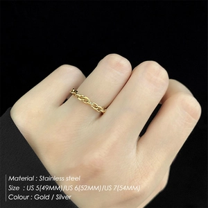 Macro detail of gold stainless steel link ring with size guide on black background