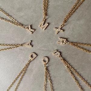 Detail of 14K gold plated initial necklaces with sparkling white zircon pavé settings