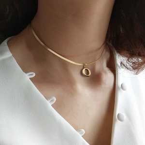 Primer plano de un collar de cadena de serpiente dorada con colgante circular en modelo
