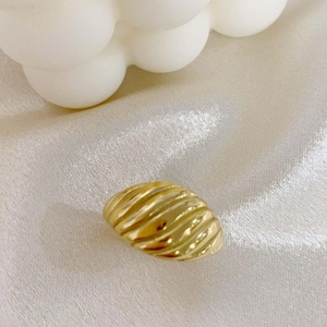 Vue rapprochée d'une bague torsadée dorée style croissant sur tissu en soie beige